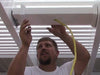Picture of a man installing a fan mount in between 2 rafters