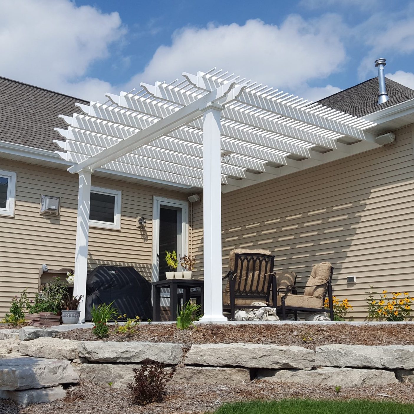 White attached aluminum-reinforced vinyl pergola with a traditional slatted roof