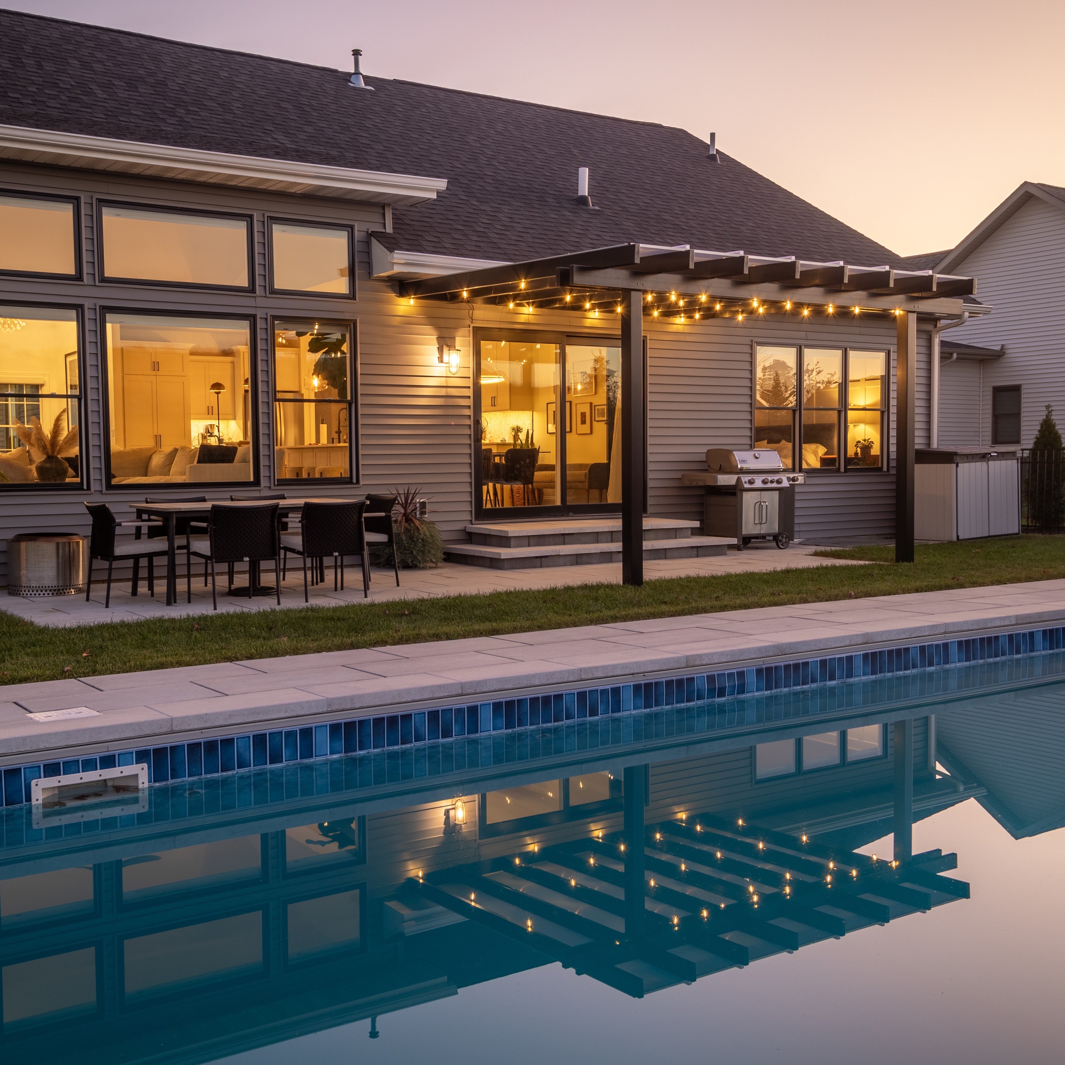 Black attached rainproof patio cover with a white polycarbonate roof overlooking a pool