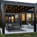 A straight-on view of a black vinyl modern-style pergola covering patio furniture on a cement patio, with large lights hanging from the rafters of the pergola to provide light in the evening and at night