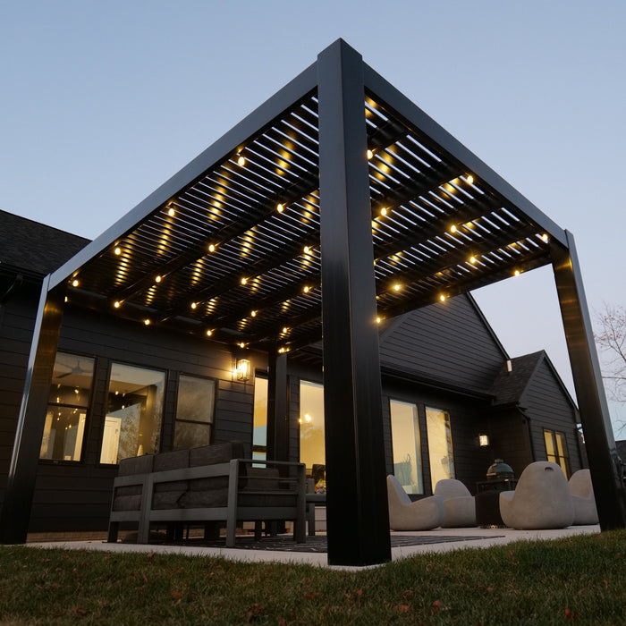 A fairly close-up view of the corner of a black vinyl free-standing modern pergola looking up towards the roof of the pergola, which has lights attached to the rafters