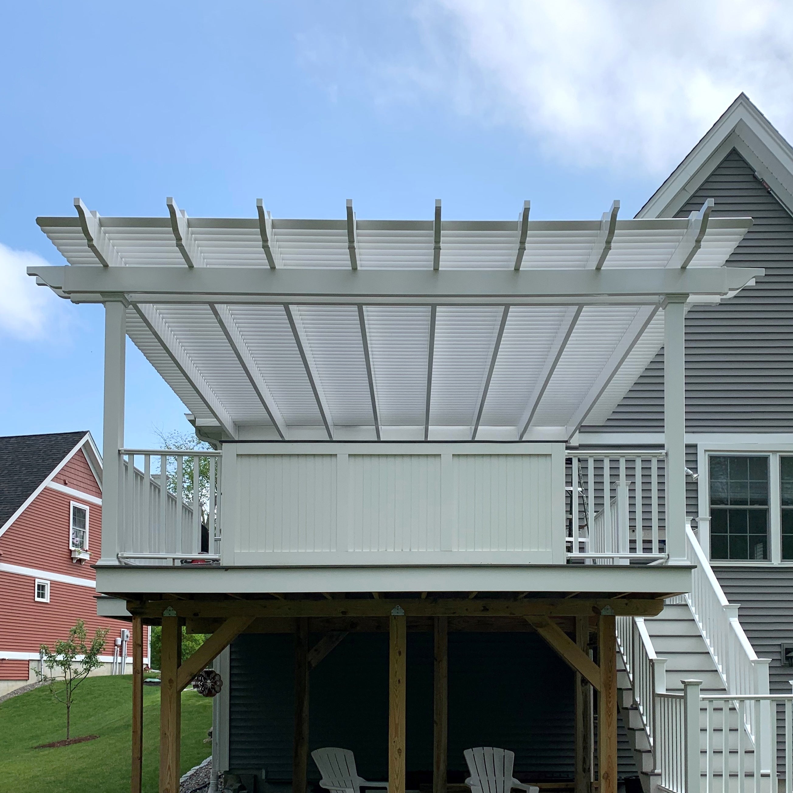 traditional attached vinyl pergola with two outer support posts and a slatted roof