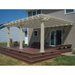 Picture of a tan vinyl traditional pergola with overhangs mounted to the outside wall of a home, with an outdoor patio table and chairs underneath the pergola