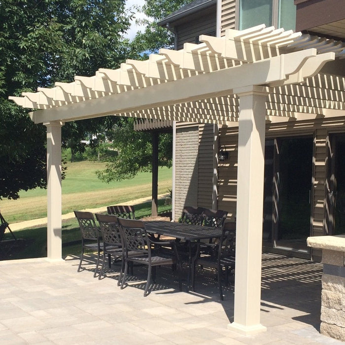 Picture of a tan vinyl traditional pergola with overhangs mounted to the outside wall of a home, with an outdoor patio table and chairs underneath the pergola