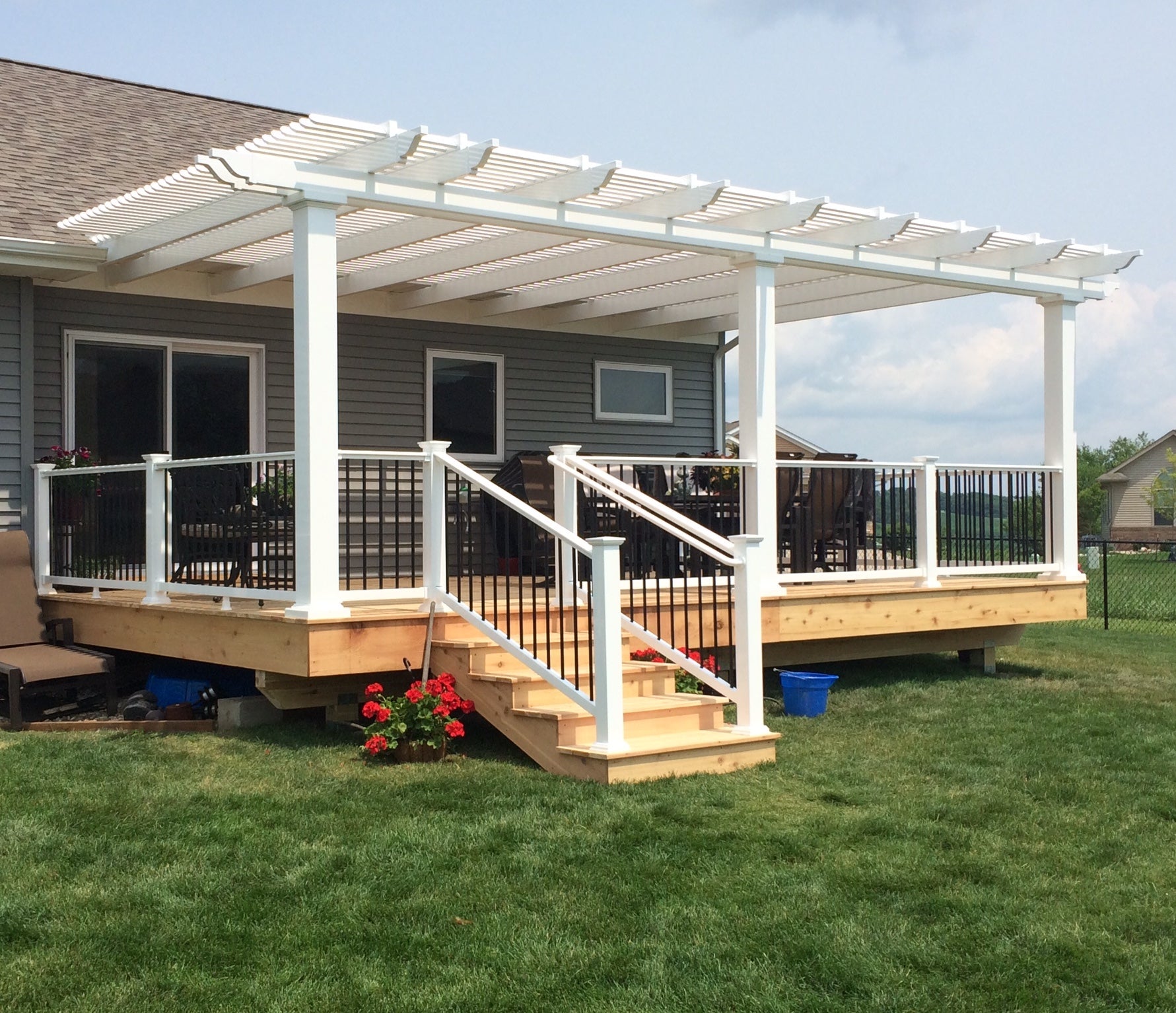 Picture of a white traditional attached pergola covering an unfinished raised deck on the back of a home