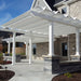 Picture of 2 side-by-side pergolas providing shade for a large L-shaped cement patio area behind a large 2-story stone house