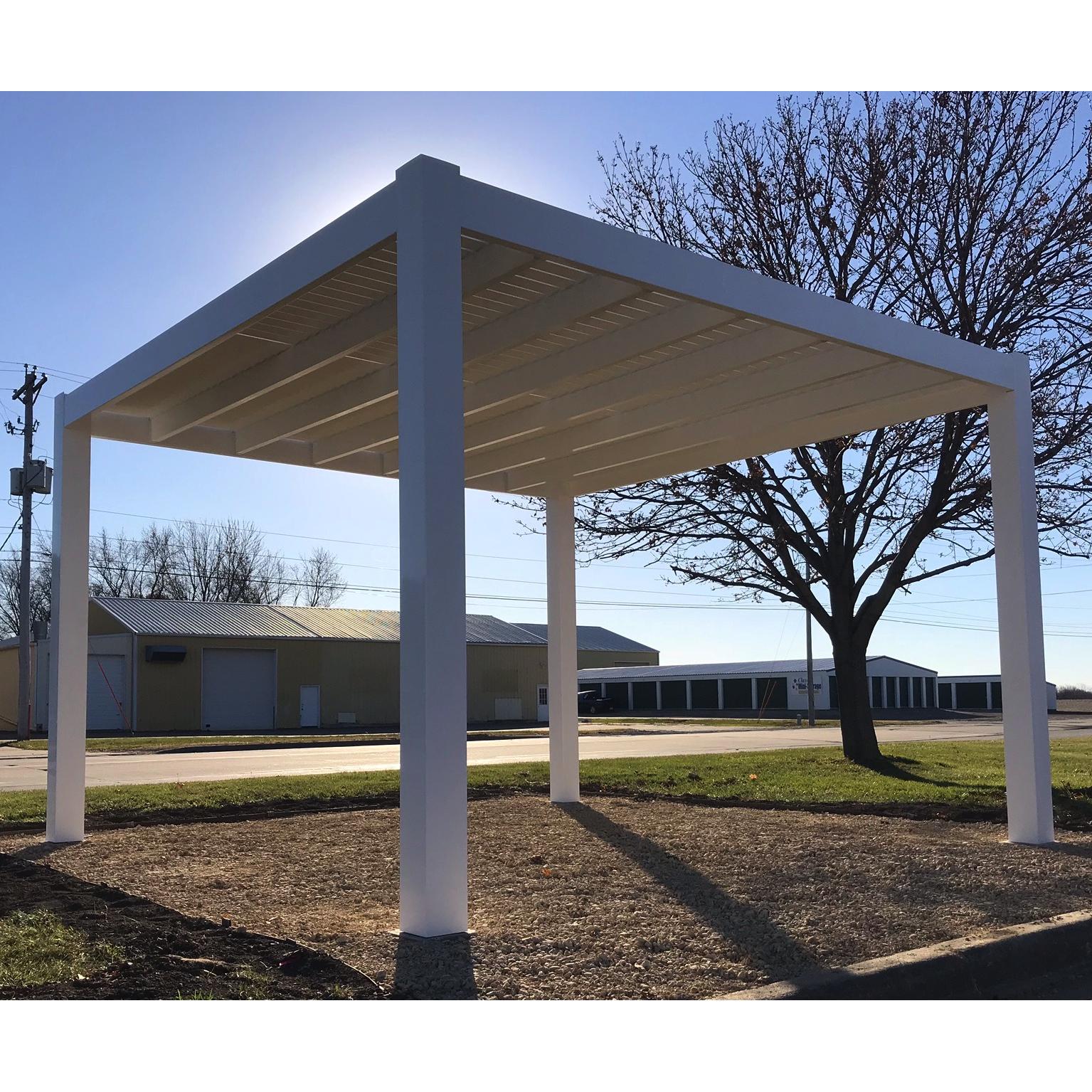 Picture of a 4-post stand-alone modern pergola covering a dirt area next to a road with commercial building across the street in the background