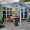 Side view of a traditional white attached pergola with 2 posts and 8 rafters covering a backyard patio with several pieces of patio furniture