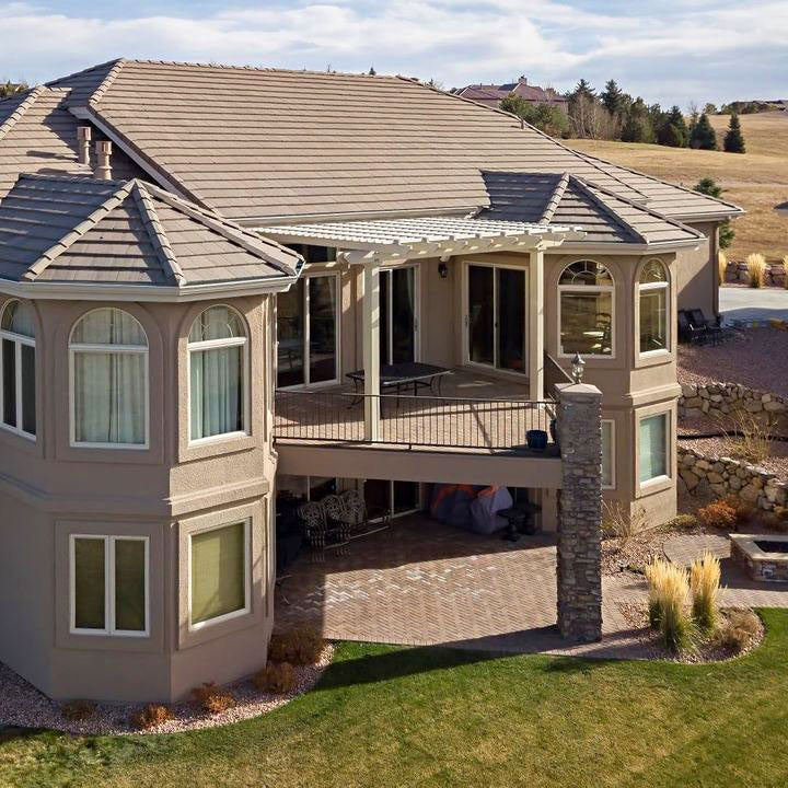 Aerial view of a beautiful house with a vinyl tan pergola attached to house covering the upper back deck