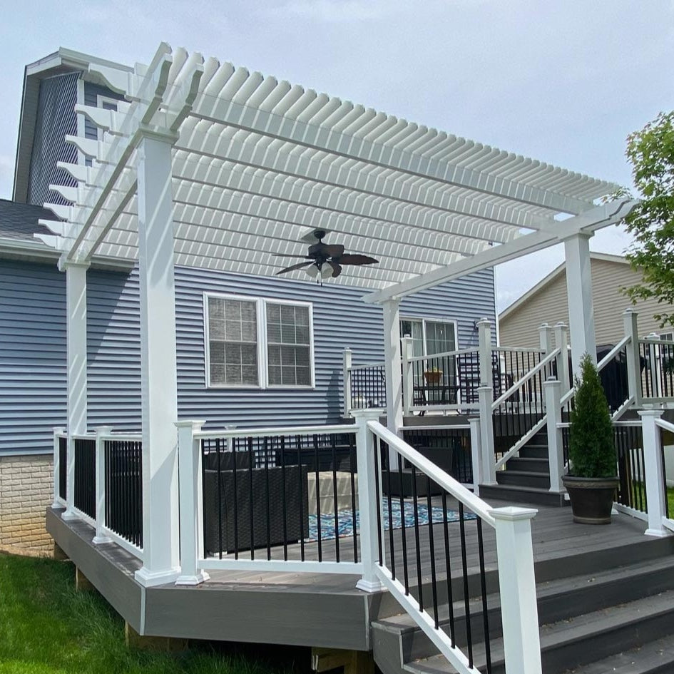Picture of a multi-level deck in front of a blue house with a 4-post white vinyl pergola covering the nearest deck