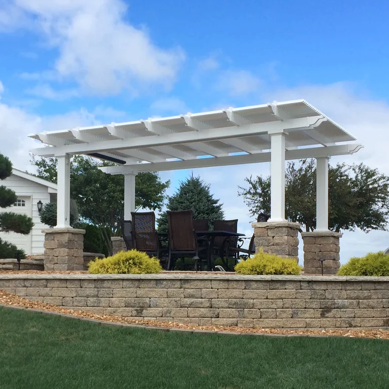 Picture of a vinyl white pergola with 4 posts covering an outdoor patio and dining set above a grassy hill