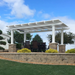 Picture of a vinyl white pergola with 4 posts covering an outdoor patio and dining set above a grassy hill