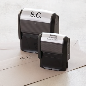 Close-up picture of 2 self-inking stamps sitting on top of a couple of envelopes