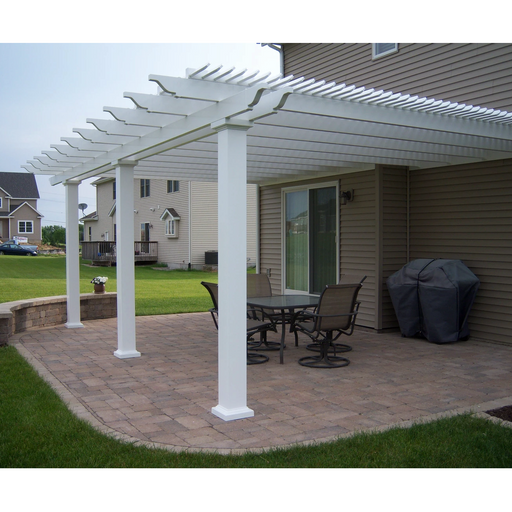 Side view of a traditional white attached pergola with 2 posts and 8 rafters covering a backyard patio with several pieces of patio furniture